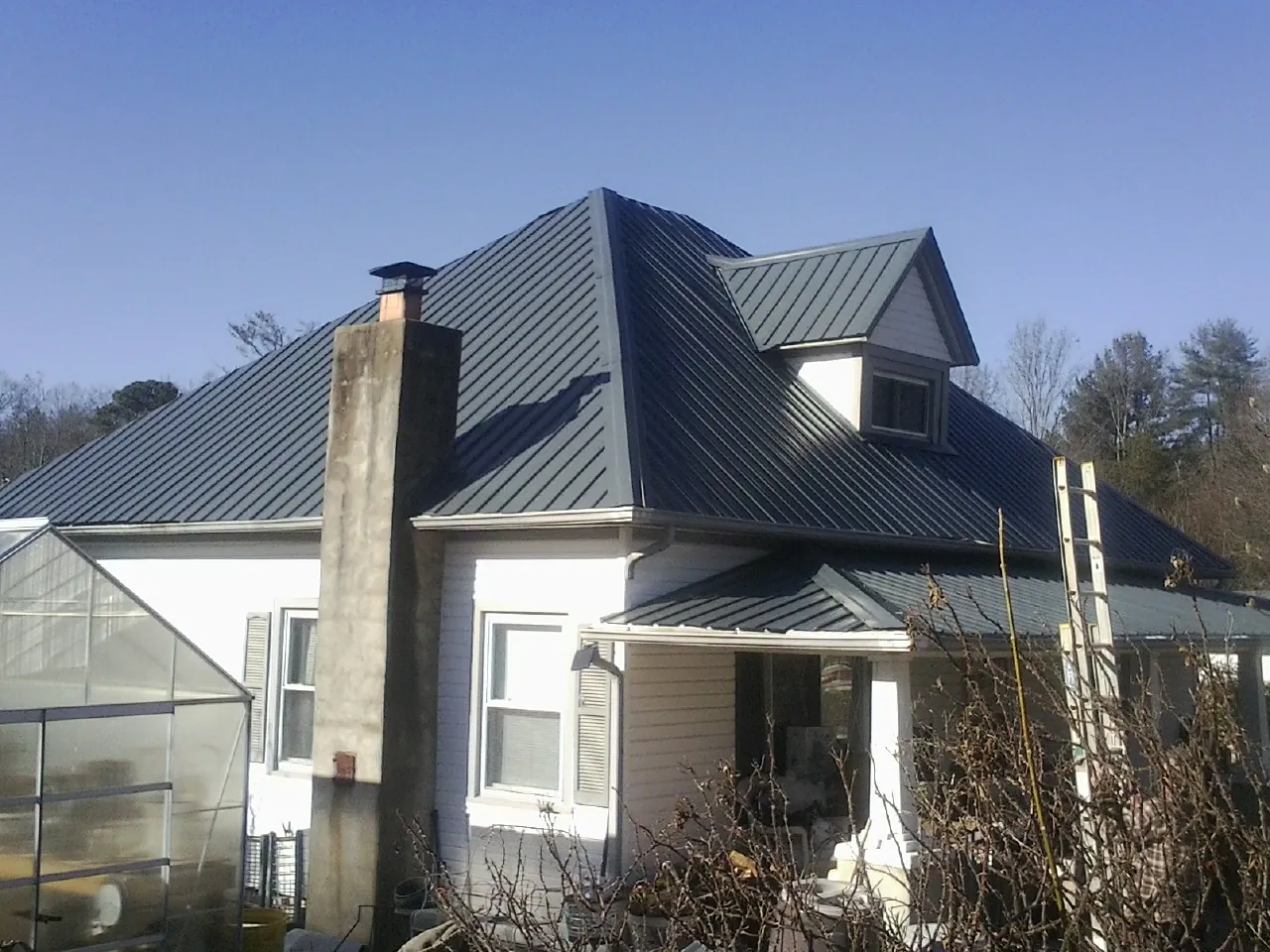 Dark blue standing seam metal roof on a white farmhouse with dormer — Slate & Tile Roof Repair by Roofing Brothers in Deepwater