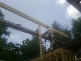 Carpenter setting a ridge beam over a new addition frame — Ice Dam Removal by Roofing Brothers in Deepwater