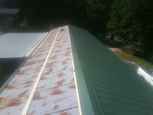 Old rusted panels beside newly installed green metal roofing — Wind Damage Roof Repair by Roofing Brothers in Deepwater