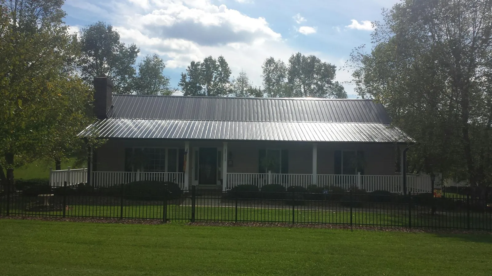 Gray metal roof on a brick ranch with a full width front porch — Gutter Guard Installation work by our crew in Deepwater