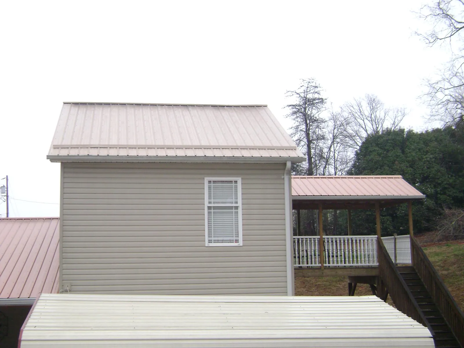 Tan metal roofs on a two story addition and attached porch, from a Roof Replacement job in Deepwater